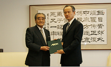 崔駐日中国大使(右)に、緊急支援金の目録を贈呈する岡田名誉会長