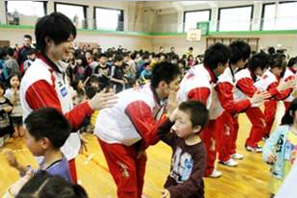 汐見小学校体育館で内村選手とハイタッチする子どもたち