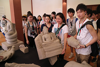 石像の模造品に触れ、大きさを体感する日本高校生
