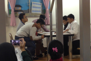 起震体験室でテーブルにつかまり揺れに耐えるインドネシア高校生