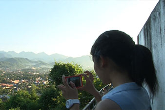 プーシーの丘の頂上にてルアンプラバンの町を撮影する日本高校生