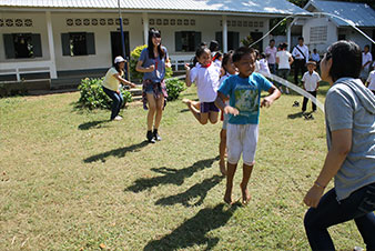 ラオス小学生と一緒に大縄跳びをする日本高校生